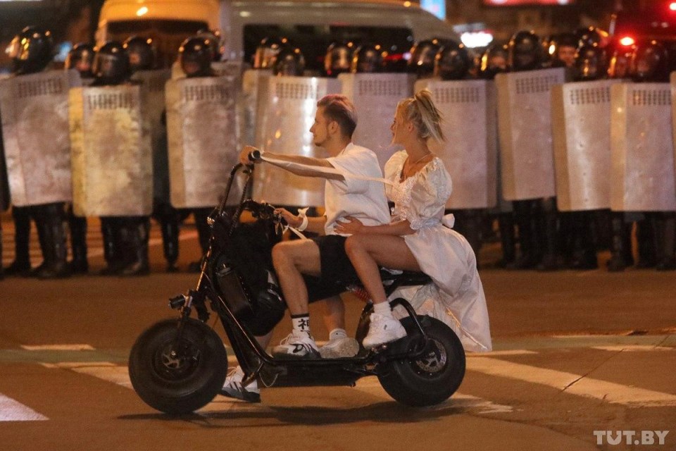 A couple ride a motorcycle through the chaotic protests