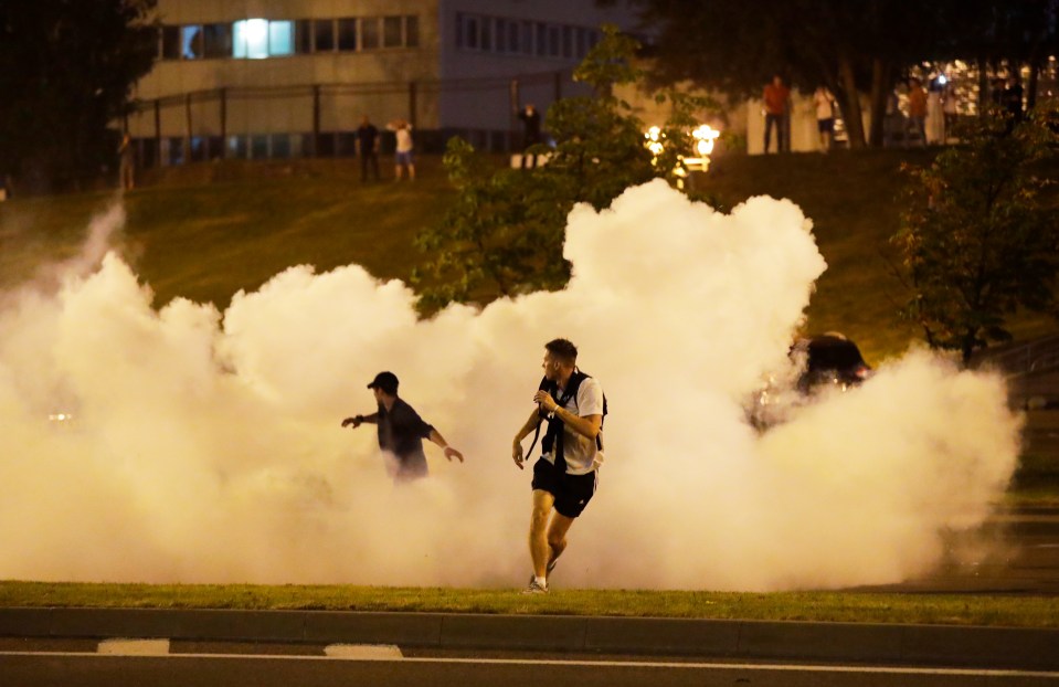 Protesters run through smoke during a protest after the Belarusian presidential election in Minsk