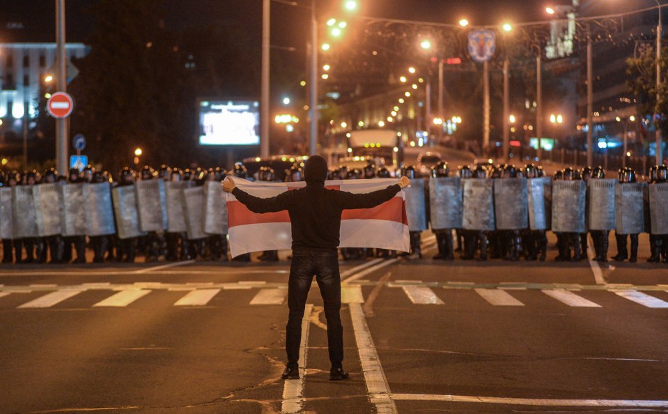 Riot police armed with shield face off against a defiant protester 