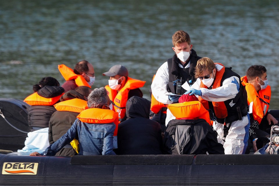 Border Force crews attend to migrants on a vessel in the harbour at Dover