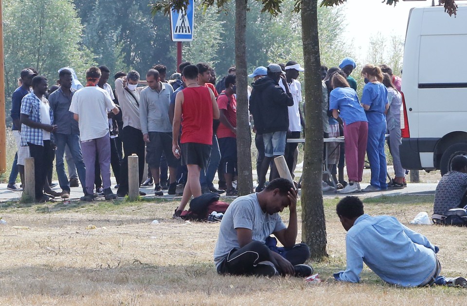 Migrants gather at the jungle camp in Calais to receive food and water from volenteers