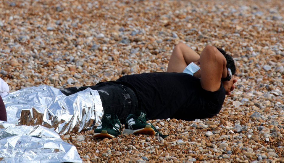 A man rests after landing in Dungeness, Kent today