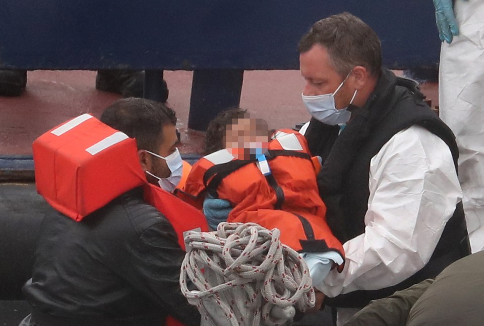  A rescue worker hands a child to their dad at Dover