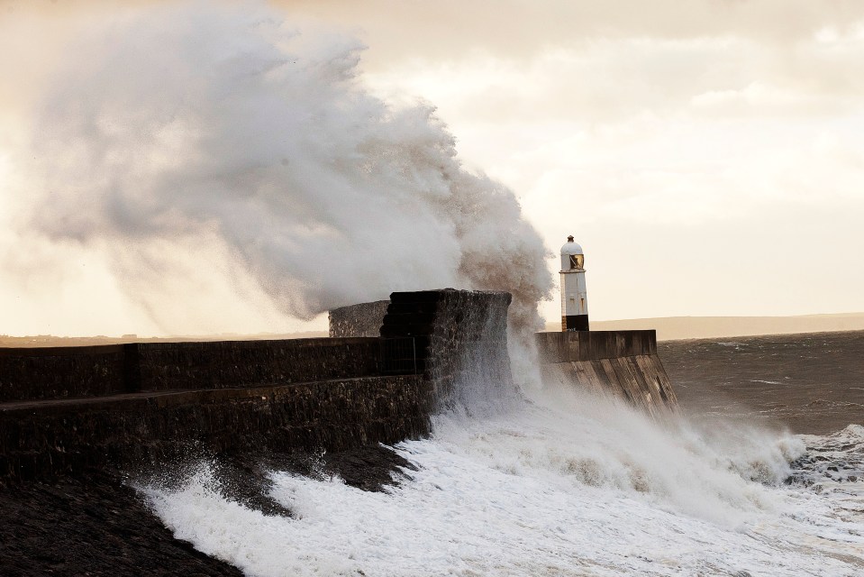 Waves smash against a lighthouse at Porthcawl, Bridgend