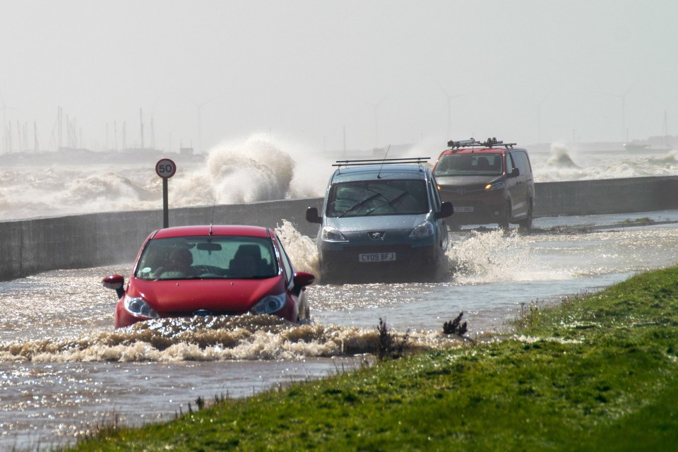 Drivers risk the waves on a coastal road in Cumbria yesterday afternoon