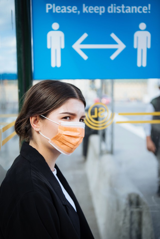 A young woman wears a face mask at a bus stop in Stockholm, Sweden on August 3