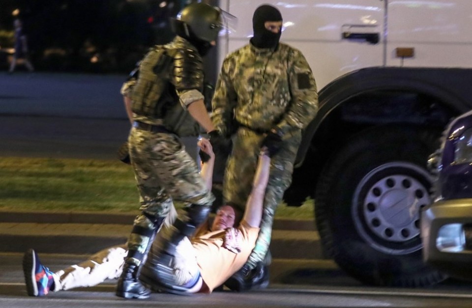 A demonstrator is dragged along the ground by masks military police in Belarus