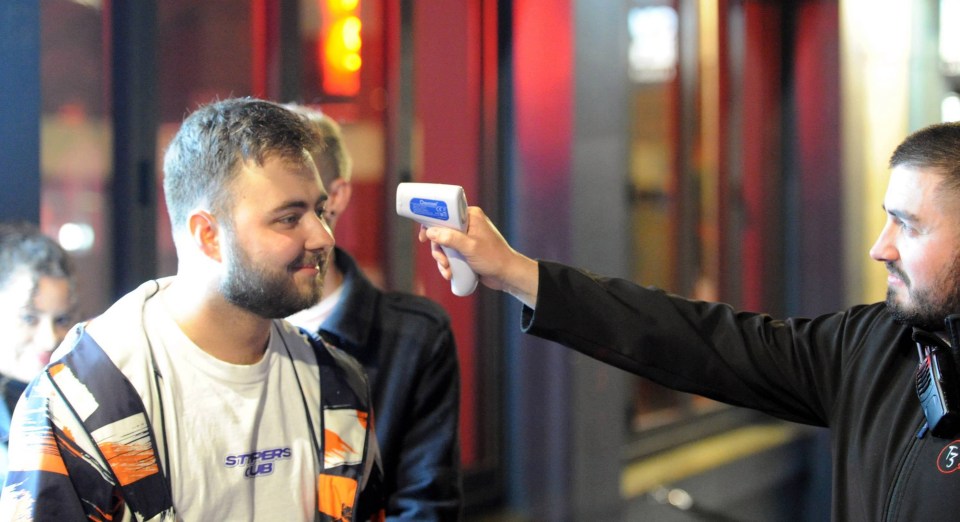 A boozer has his temperature checked as he goes into a bar