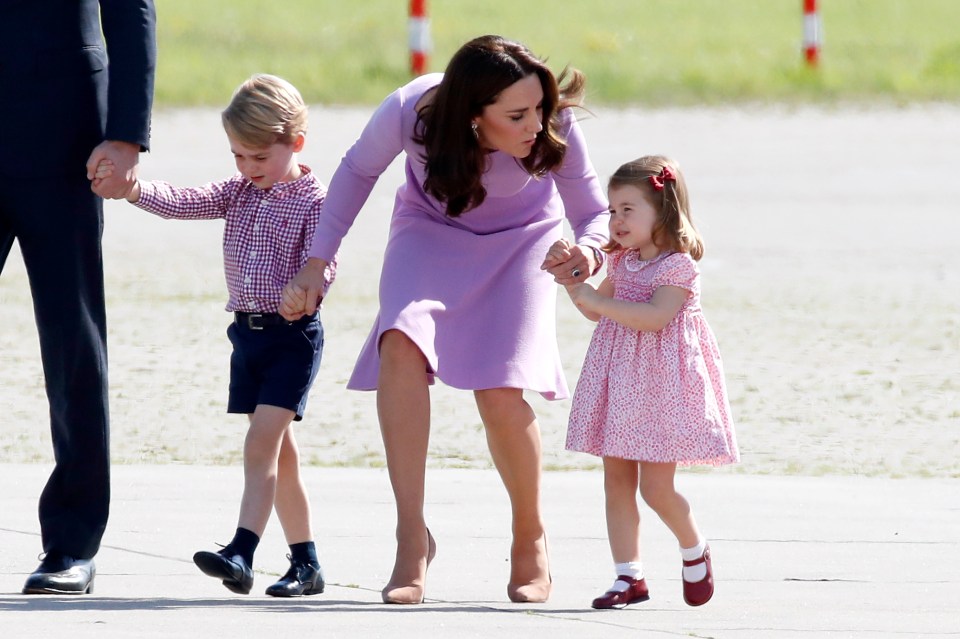 a woman in a purple dress holds hands with two children