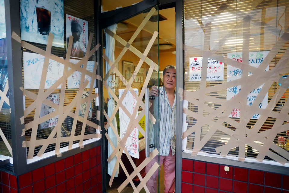 A coffee shop owner tapes his shop windows in the city of Uwajima