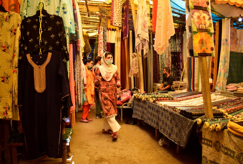 A woman shops for saris while wearing a protective face mask