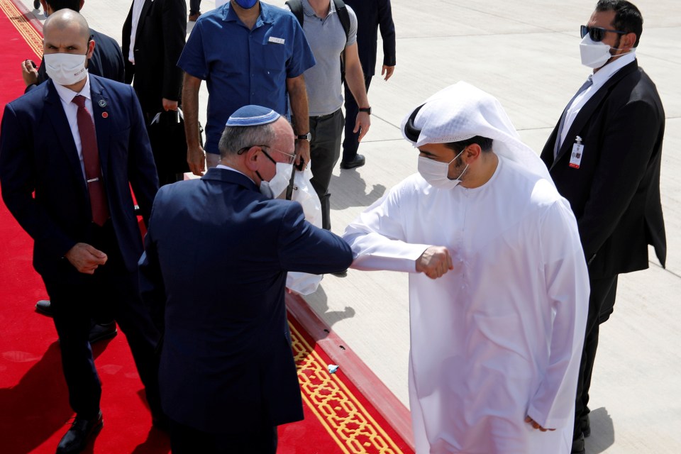 Israeli National Security Adviser Meir Ben-Shabbat elbow bumps with an Emirati official as he makes his way to board the plane to leave Abu Dhabi after agreeing to a peace deal