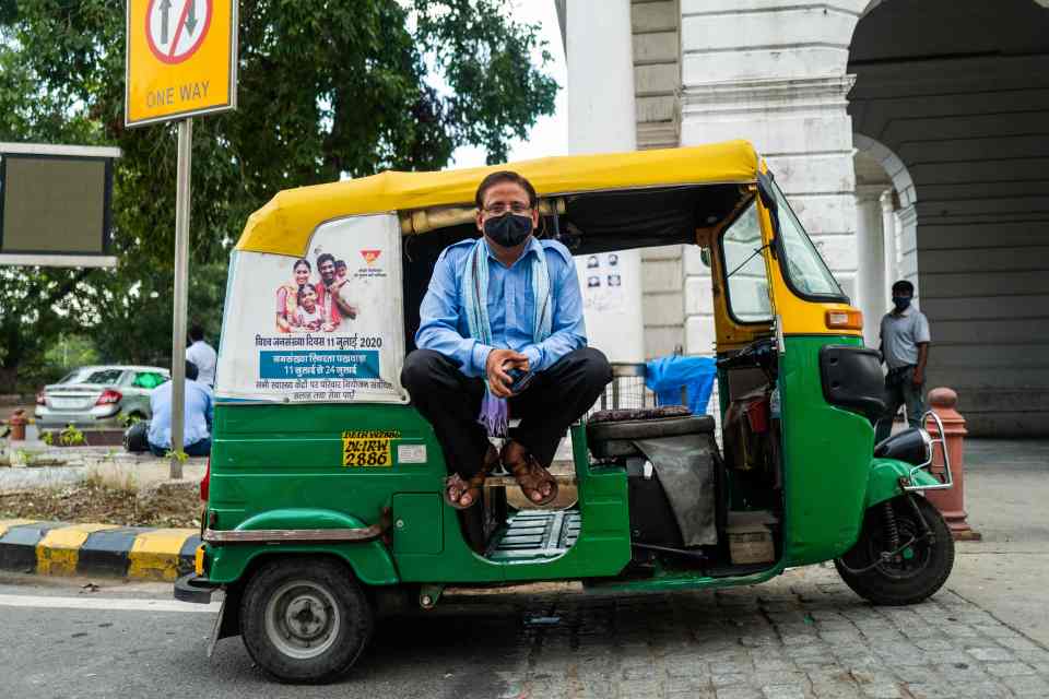 A rickshaw driver wears a facemask as he waits for passengers in New Delhi