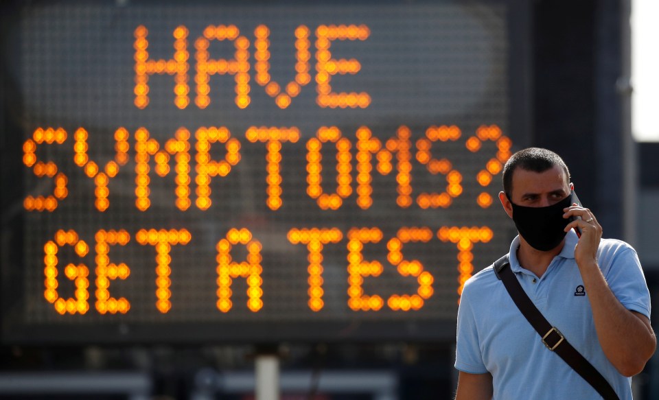 A man walks passed a sign in virus-ravaged Bolton 