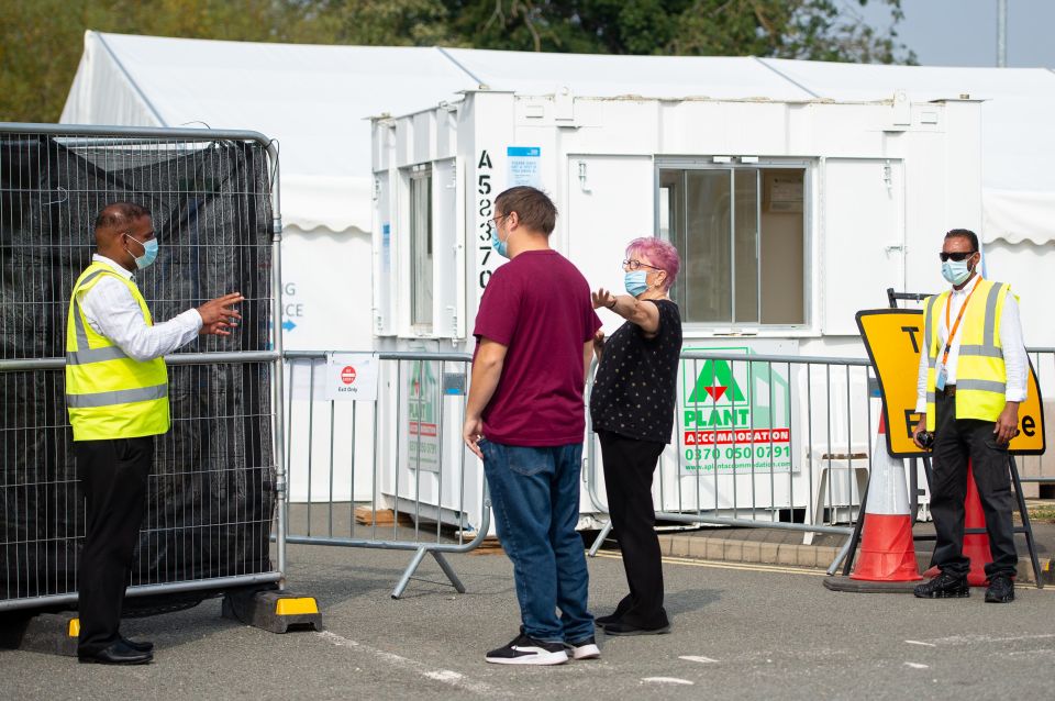 A man waits outside a testing centre in Bedford, Bedfordshire today