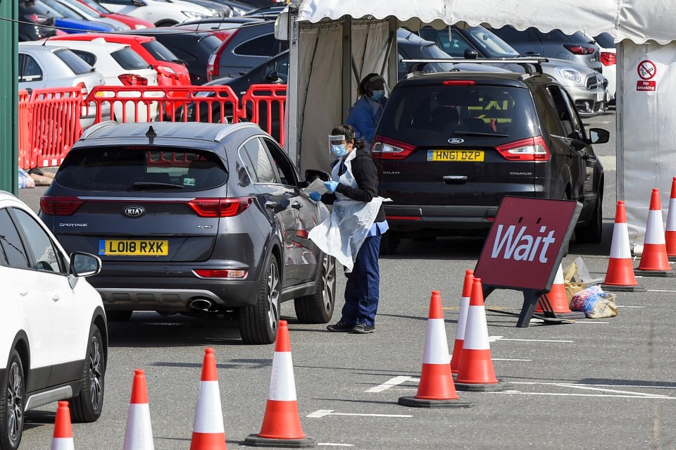 A staff member prepares to administer a test to a driver in their car at the Covid-19 testing centre outside Watford General Hospital 