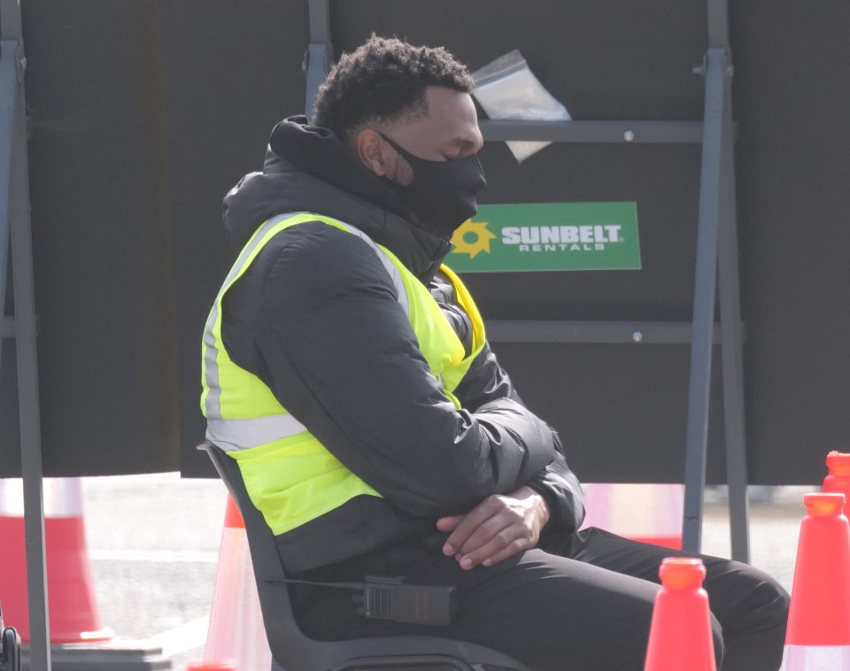 A worker at a deserted Heathrow coronavirus testing centre dozes off