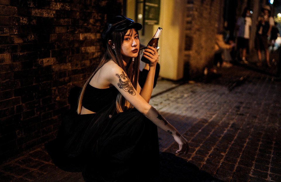 A girl sits outside with a bottle of drink