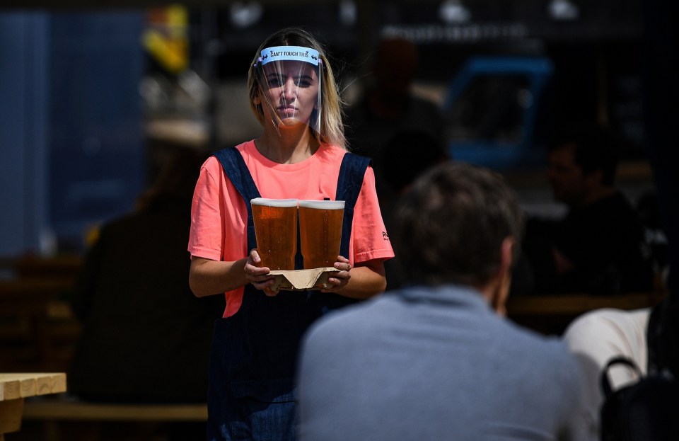 A woman wearing PPE carries two pints of beer in Glasgow