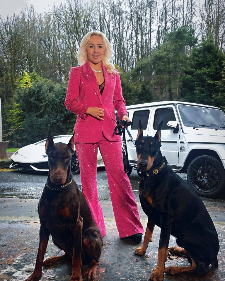 a woman in a pink suit is standing next to two dogs