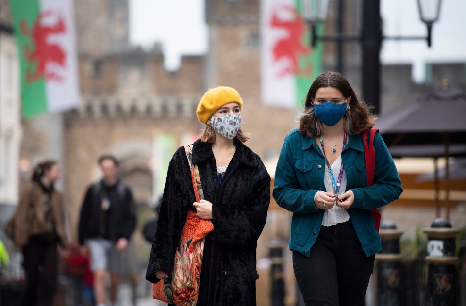 Two women wear face masks as they walk down St Mary Street near Cardiff Castle on October 18, 2020