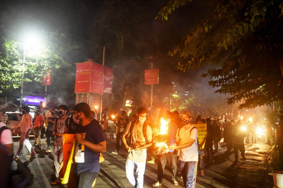 Students hold torches as they shout slogans to protest against the government's handling of rape cases