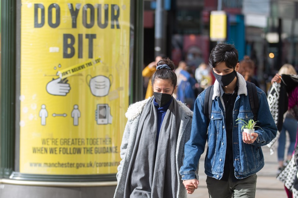 A couple walk past a sign encouraging them to do their bit to stop the spread