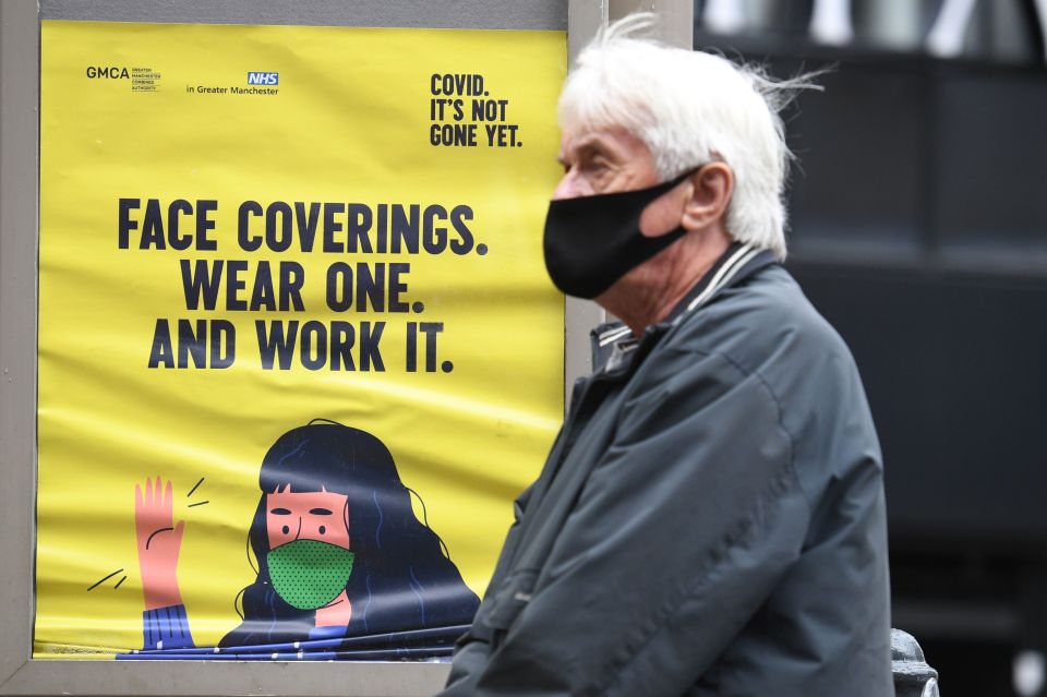 A man wears a mask in Manchester, where tighter restrictions could be enforced