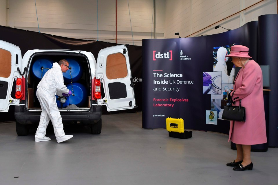 A forensic officer shows Her Majesty a model explosive device in a vehicle 