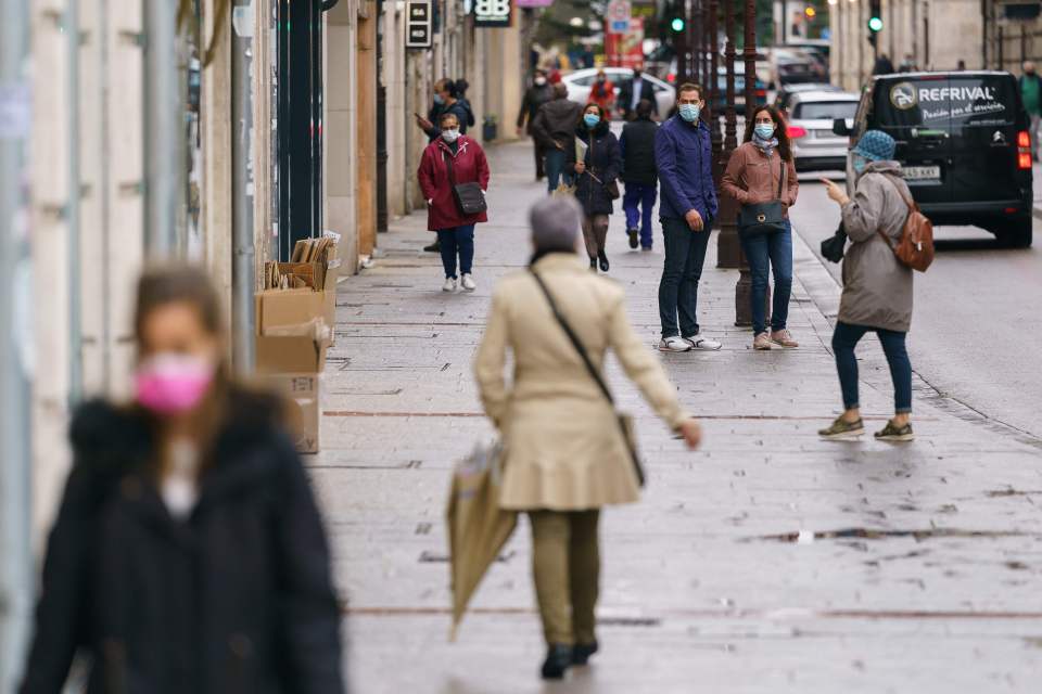 People wearing face masks walk in Burgos, northern Spain, on October 21, 2020, on the first day of a two week lockdown 