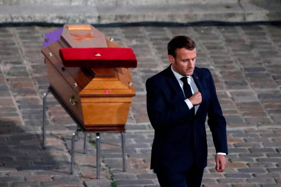 Emmanuel Macron with the teacher's coffin behind him