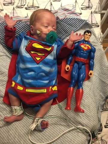 Logan pictured next to his Superman toy at 14 weeks old