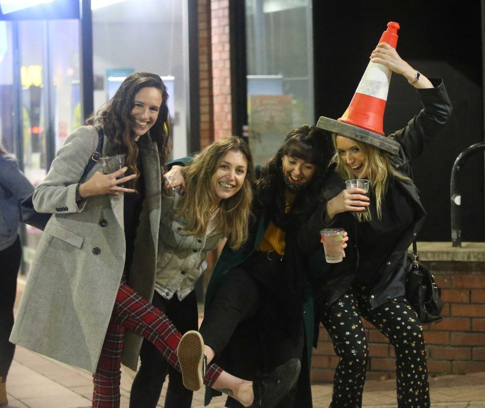 This group made use of a road cone as they posed for a picture while enjoying a drink