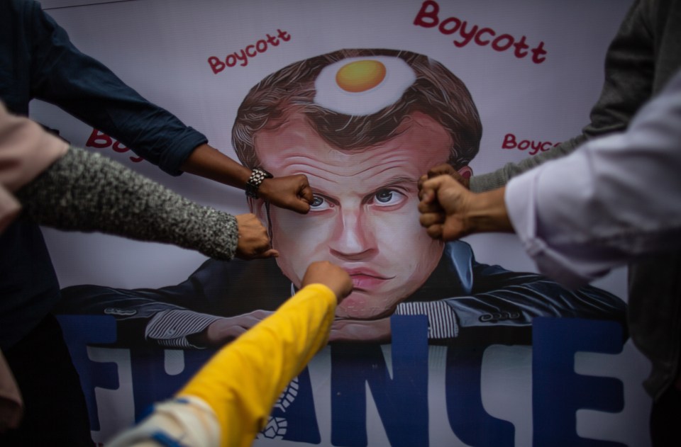 People punch a poster outside the French embassy in Jakarta, Indonesia