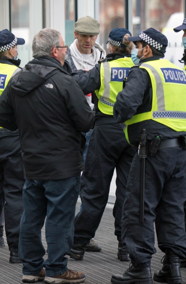 Police stop an anti-mask protester in central London this morning