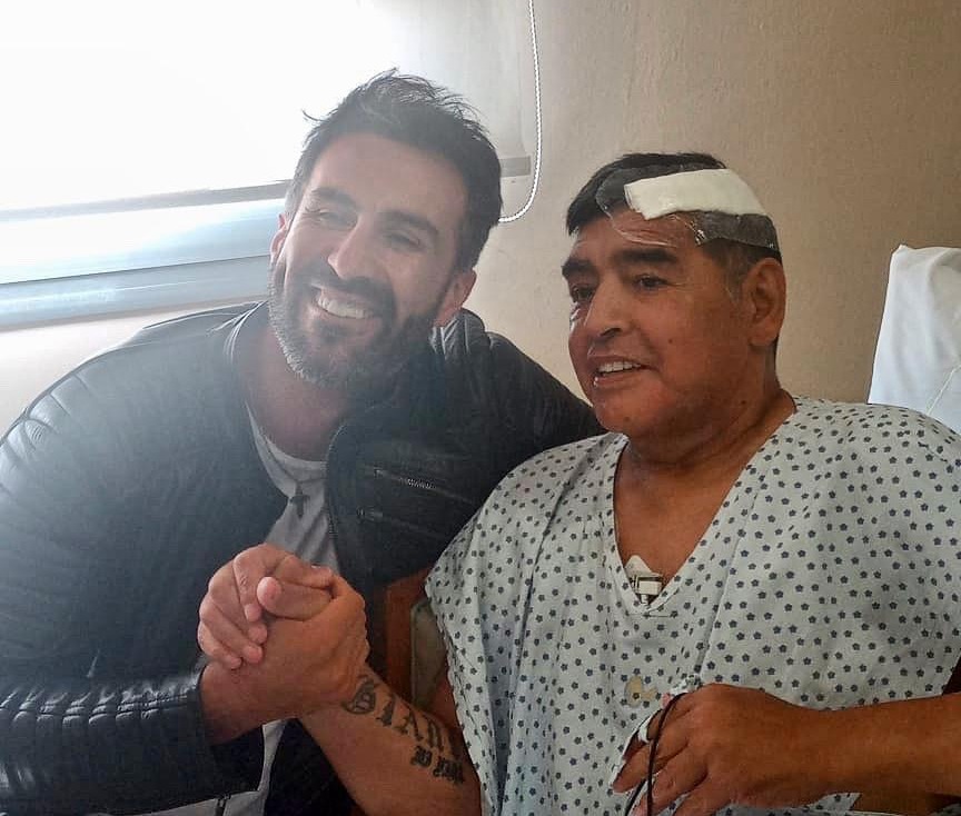 Diego Maradona is seen shaking hands with his Leopoldo Luque after undergoing surgery to remove a blood clot from his brain