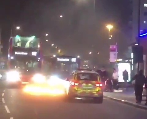 Above: police arresting a man near the bus stop while to the left, flames can be seen on the road