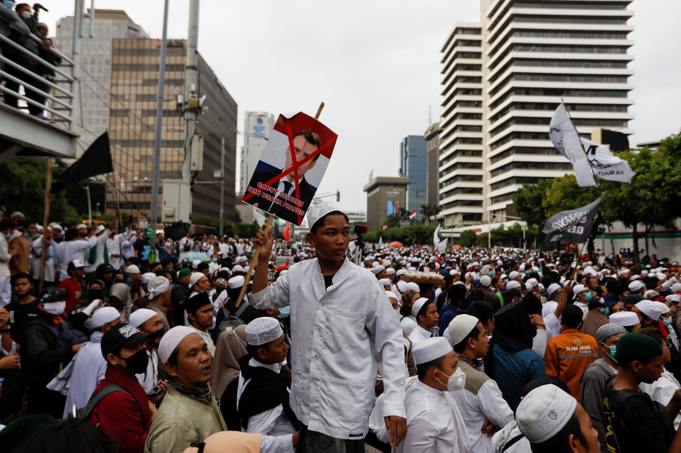 A protester holds a sign with Macron's face crossed out at a protest near the French embassy in Jakarta, Indonesia