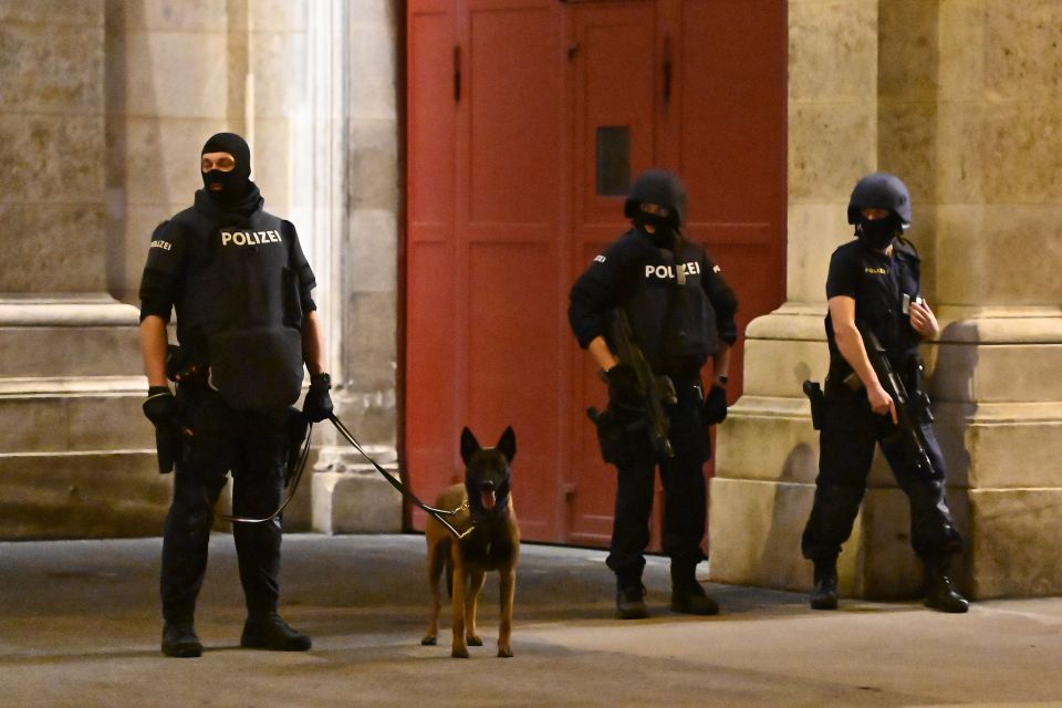 Armed cops stand with a police dog on patrol in Vienna