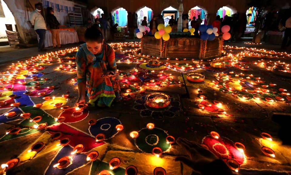 An Indian young woman lights an oil lamp at the historical Gauhar Mahal palace, as part of the Diwali festival celebrations in Bhopal, India