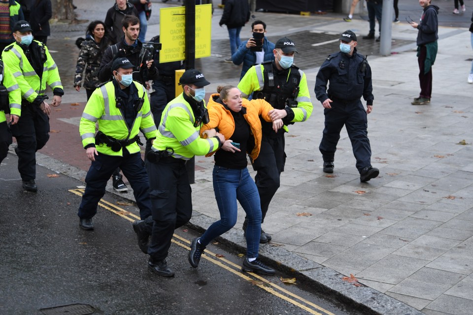 Police wearing masks appear to lead away a protester