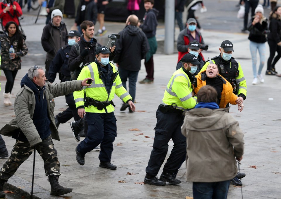 Protesters react as police lead away a woman