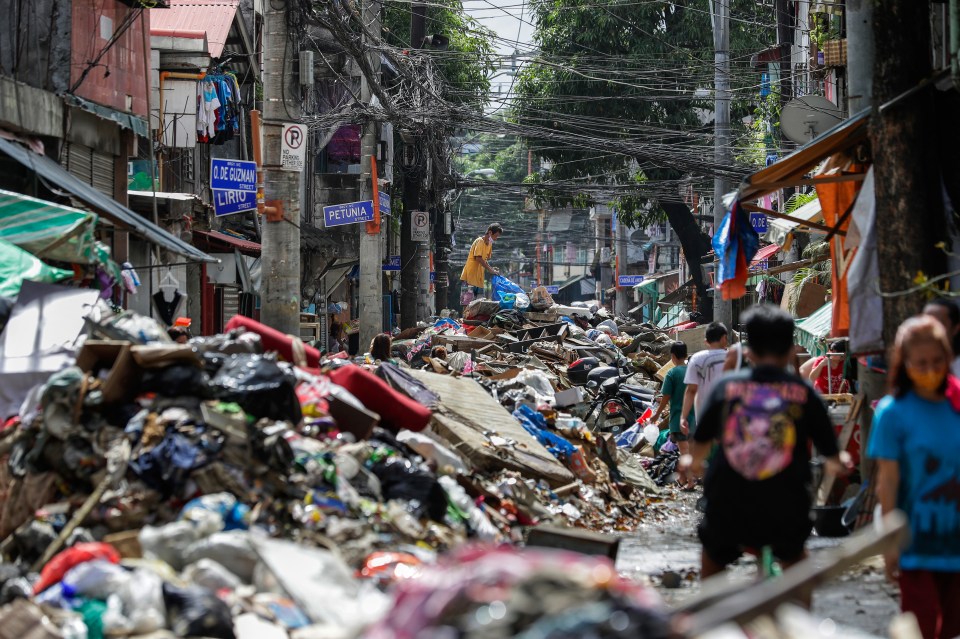 Residents climb over piles of debris washed in floodwaters from Typhoon Vamco in Marikina, Philippines