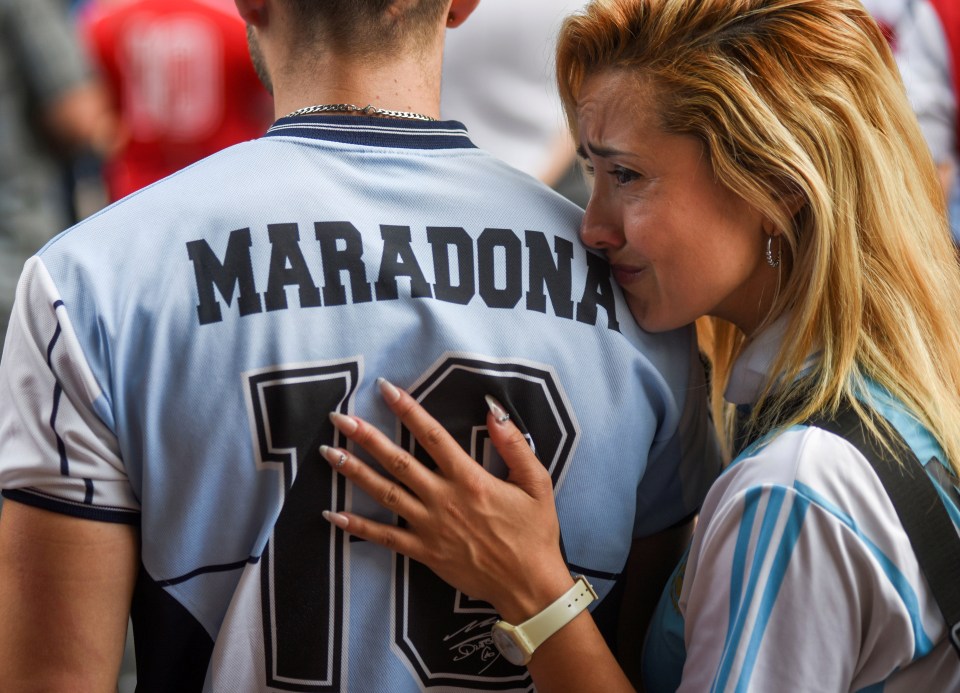 A woman struggles to hold back tears as she gathers with other fans at the Diego Armando Maradona stadium in Buenos Aires, 