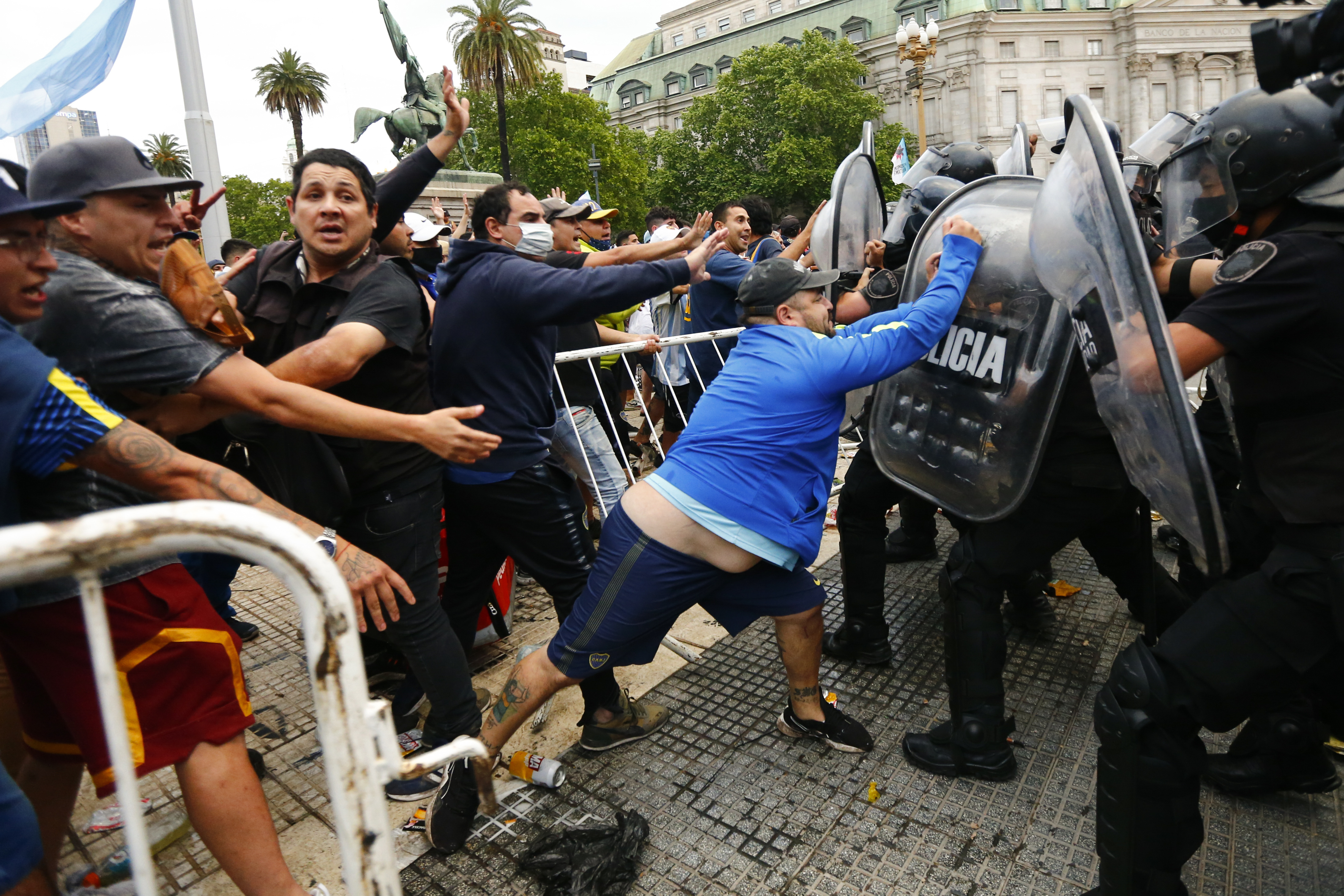 One fan pounds on the shield of a riot cop as they try to get a glimpse of their hero's casket at the presidential palace