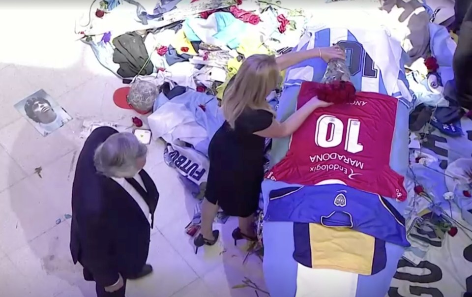 Argentina’s President Alberto Fernandez places an Argentinos Juniors jersey on the coffin as it lies in the presidential palace