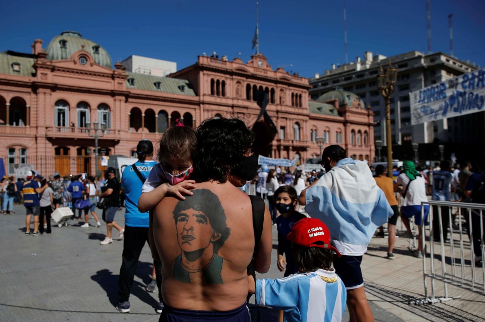 A man with a Maradona tattoo on his back arrives at the presidential palace to get a glimpse of the casket carrying the former forward