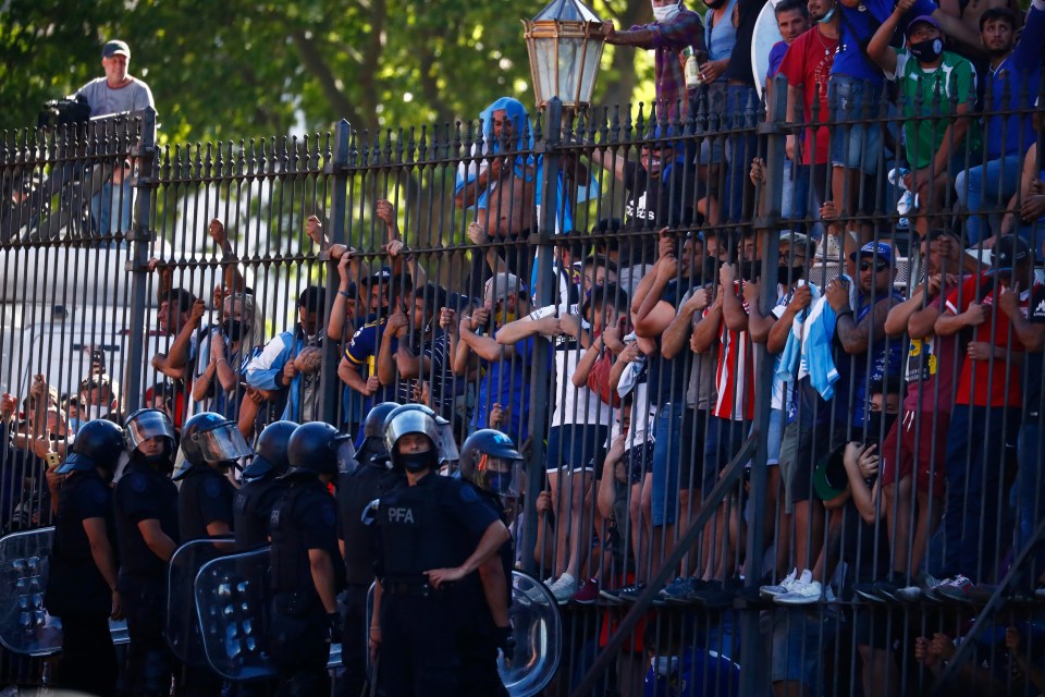 Mourning fans climb the fence of the presidential palace to get a glimpse of the casket carrying Maradona’s body 