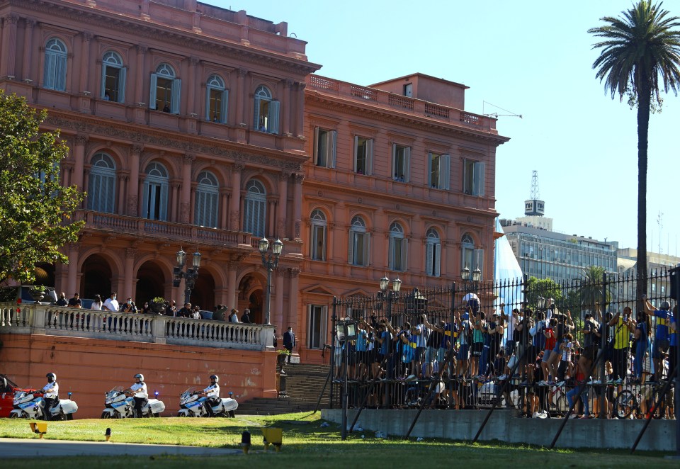 Fans wave as the funeral procession with the casket of soccer legend Maradona leaves the presidential palace Casa Rosada