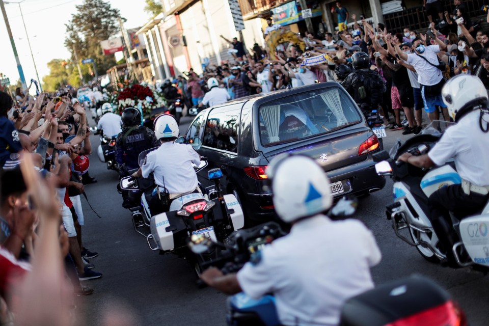 People watch Maradona’s casket go by surrounded by police in Buenos Aires